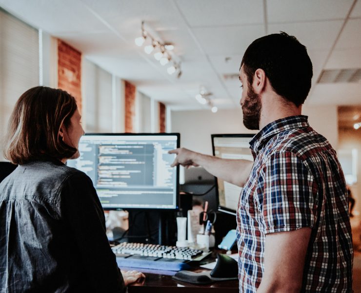 Software developers discussing code on a monitor